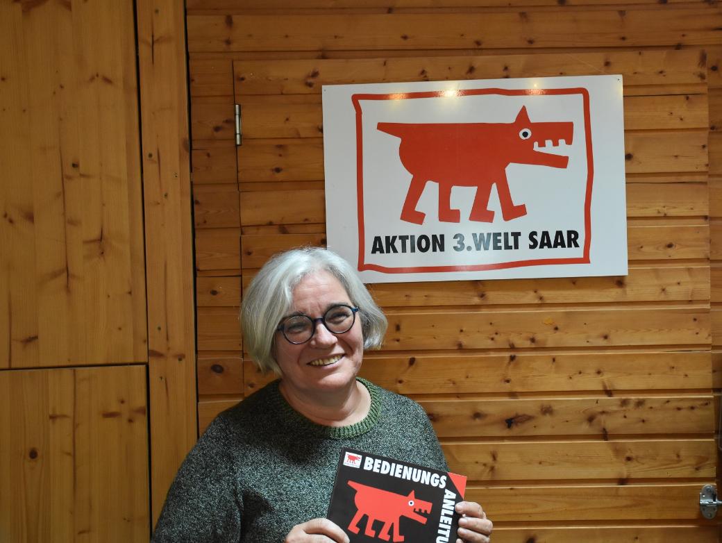Portraitbild von Gertrud Selzer. In den Händen hält sie ein Plakat der Aktion 3. Welt Saar.