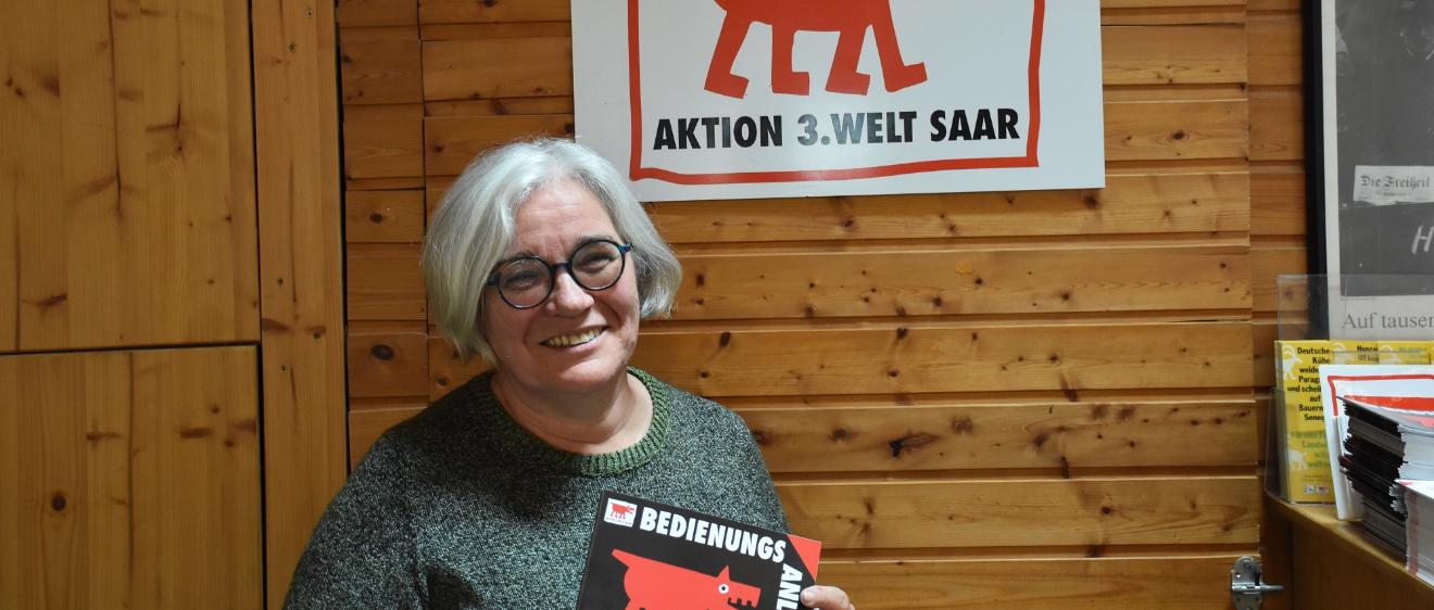Portraitbild von Gertrud Selzer. In den Händen hält sie ein Plakat der Aktion 3. Welt Saar.