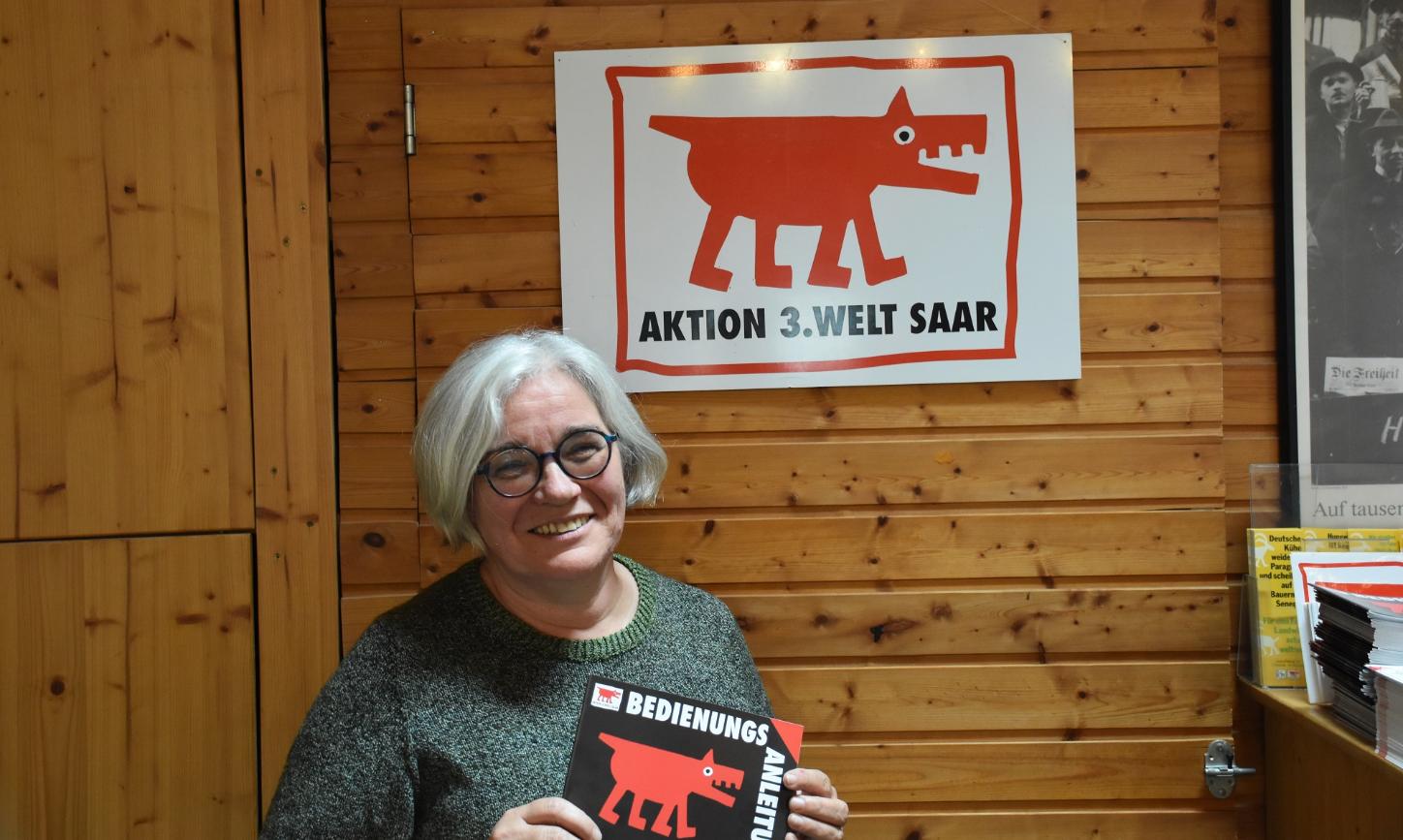 Portraitbild von Gertrud Selzer. In den Händen hält sie ein Plakat der Aktion 3. Welt Saar.