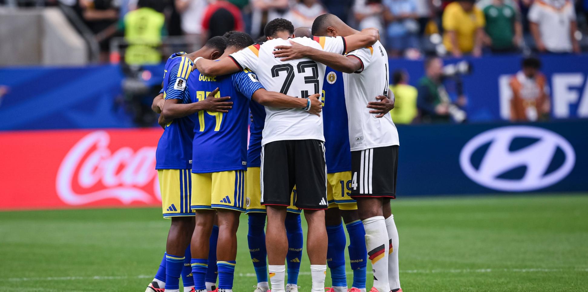 Fußballer versammeln sich nach dem Spiel im Mittelkreis und beten gemeinsam: Joshua Brenet (Curacao), Gervane Kastaneer (Curacao), Felix Nmecha (Deutschland) und Jonathan Tah (Deutschland)/von links).
