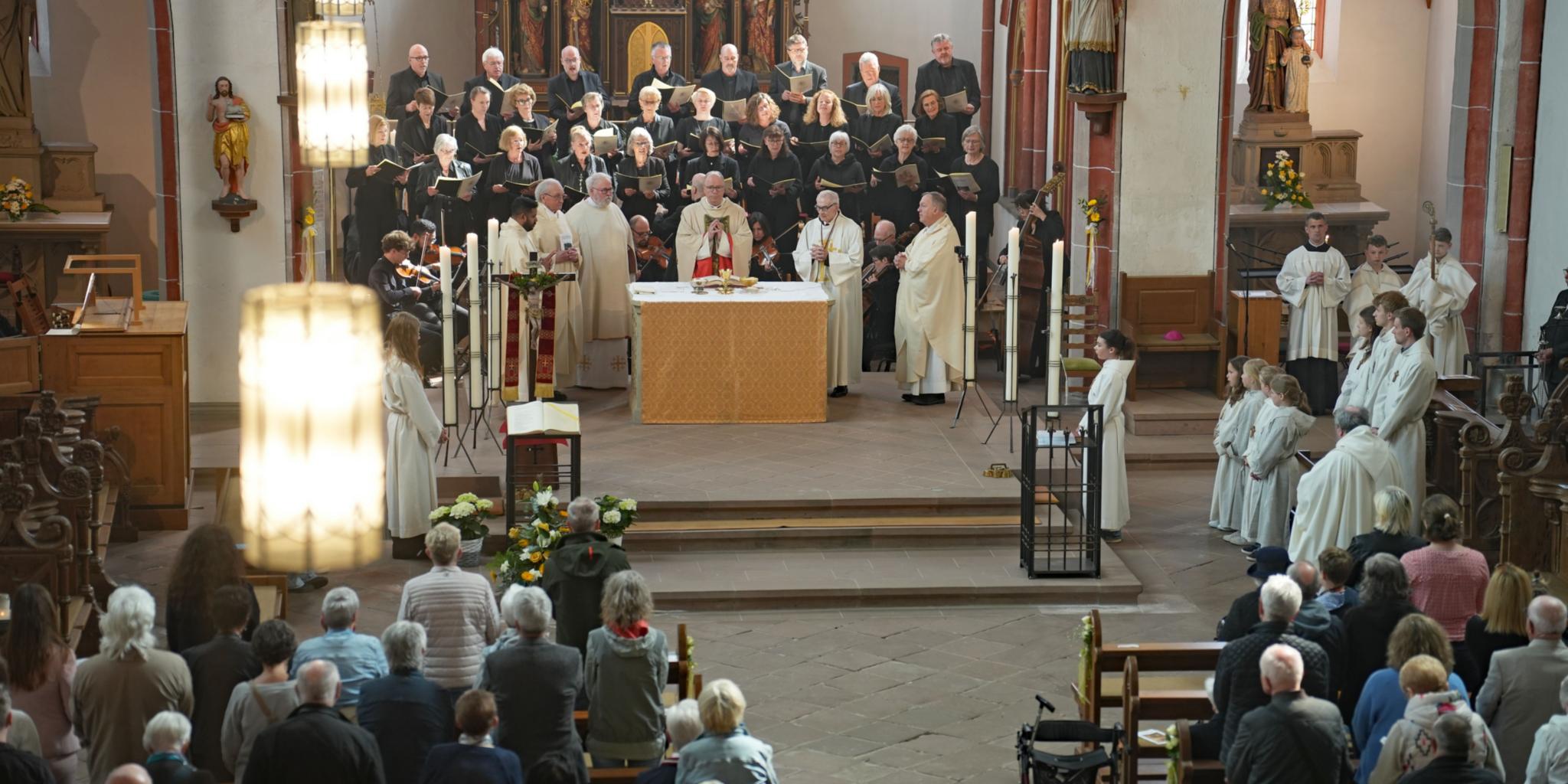 Bischof Dr. Stephan Ackermann bei der Feier des Pontifikalamtes am Altar, dahinter der Kirchenchor Cäcilia Kyllburg.