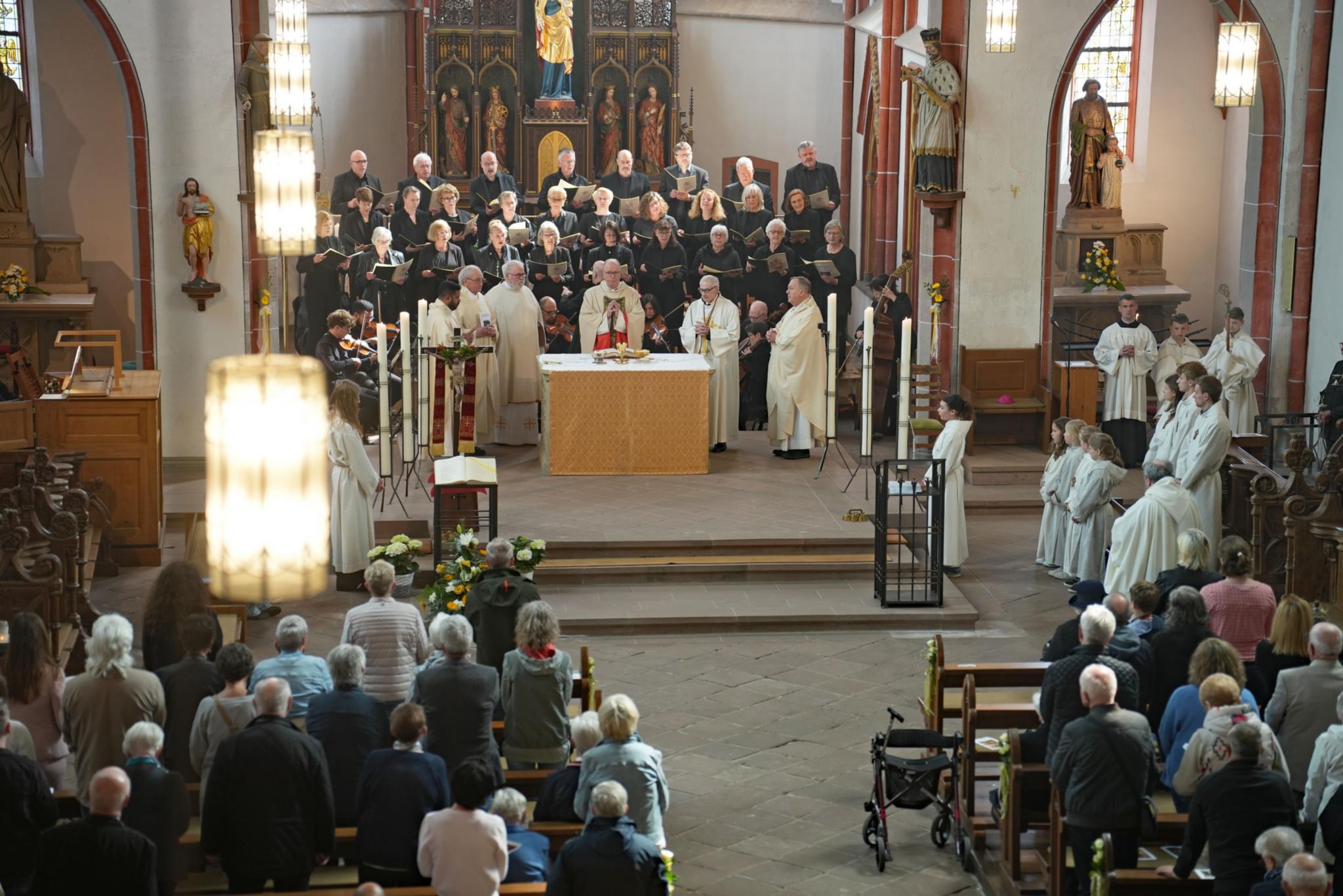 Bischof Dr. Stephan Ackermann bei der Feier des Pontifikalamtes am Altar, dahinter der Kirchenchor Cäcilia Kyllburg.