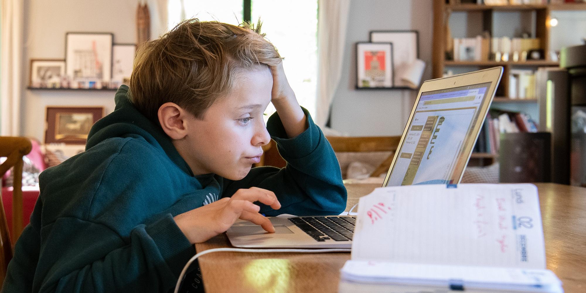 Schüler sitzt am Computer und arbeitet an seinen Hausaufgaben.