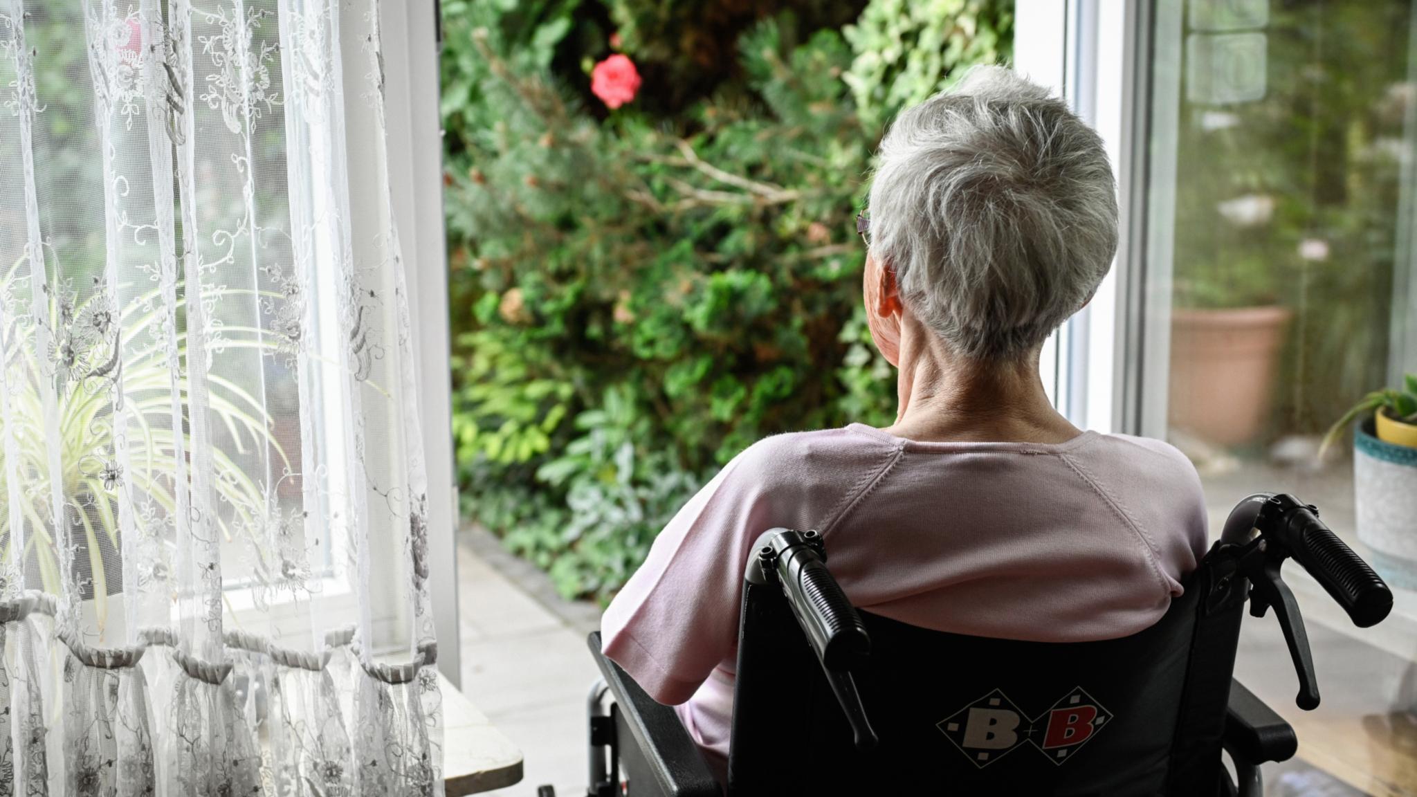 Eine Seniorin schaut in den Garten: Eine Atmosphäre, die ganz bestimmt zu ihrem Wohlbefinden beiträgt.
