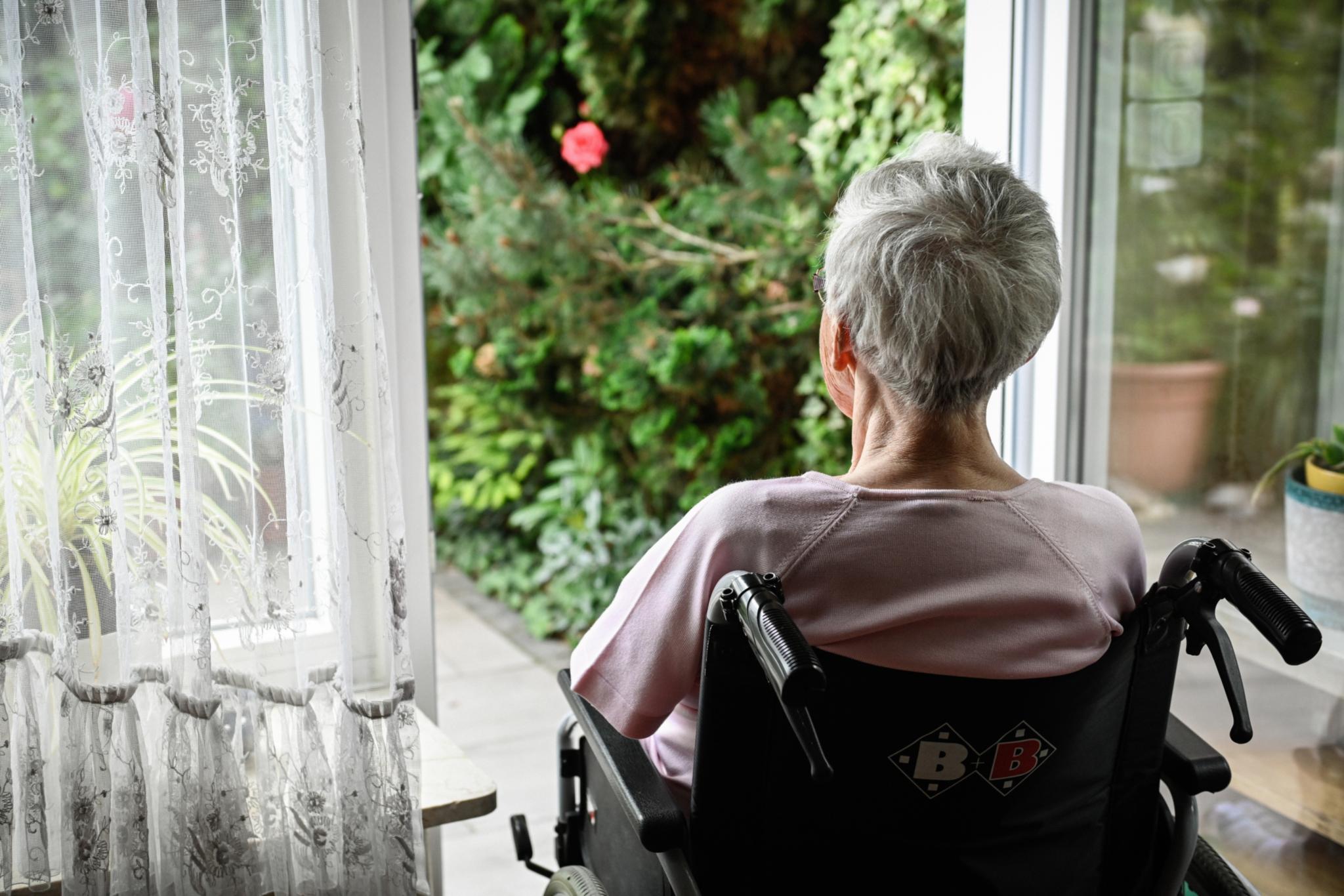 Eine Seniorin schaut in den Garten: Eine Atmosphäre, die ganz bestimmt zu ihrem Wohlbefinden beiträgt.