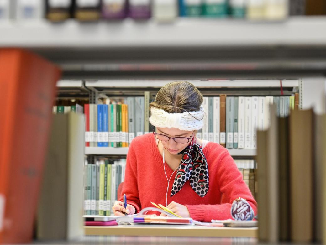 Eine Studentin sitzt in der Fachbibliothek für Evangelische und Katholische Theologie der Rheinischen Friedrich-Wilhelms-Universität Bonn.