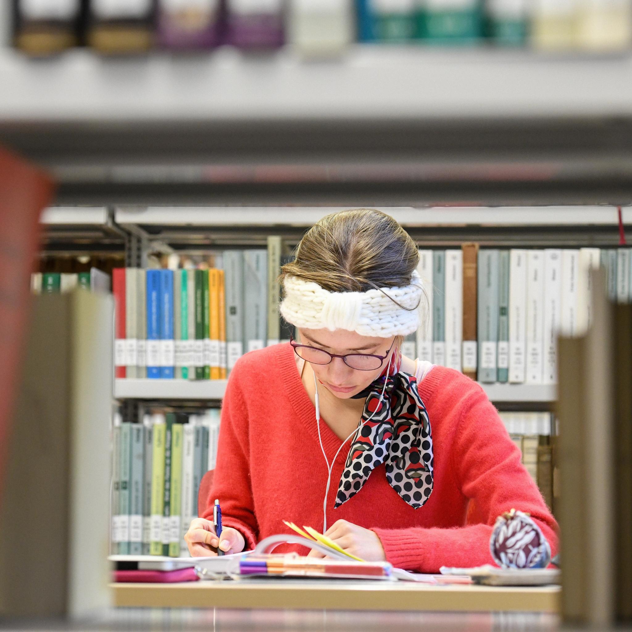 Eine Studentin sitzt in der Fachbibliothek für Evangelische und Katholische Theologie der Rheinischen Friedrich-Wilhelms-Universität Bonn.