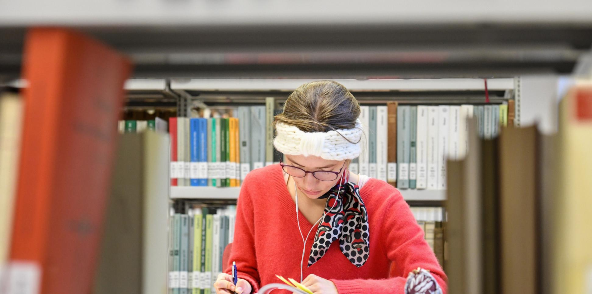 Eine Studentin sitzt in der Fachbibliothek für Evangelische und Katholische Theologie der Rheinischen Friedrich-Wilhelms-Universität Bonn.