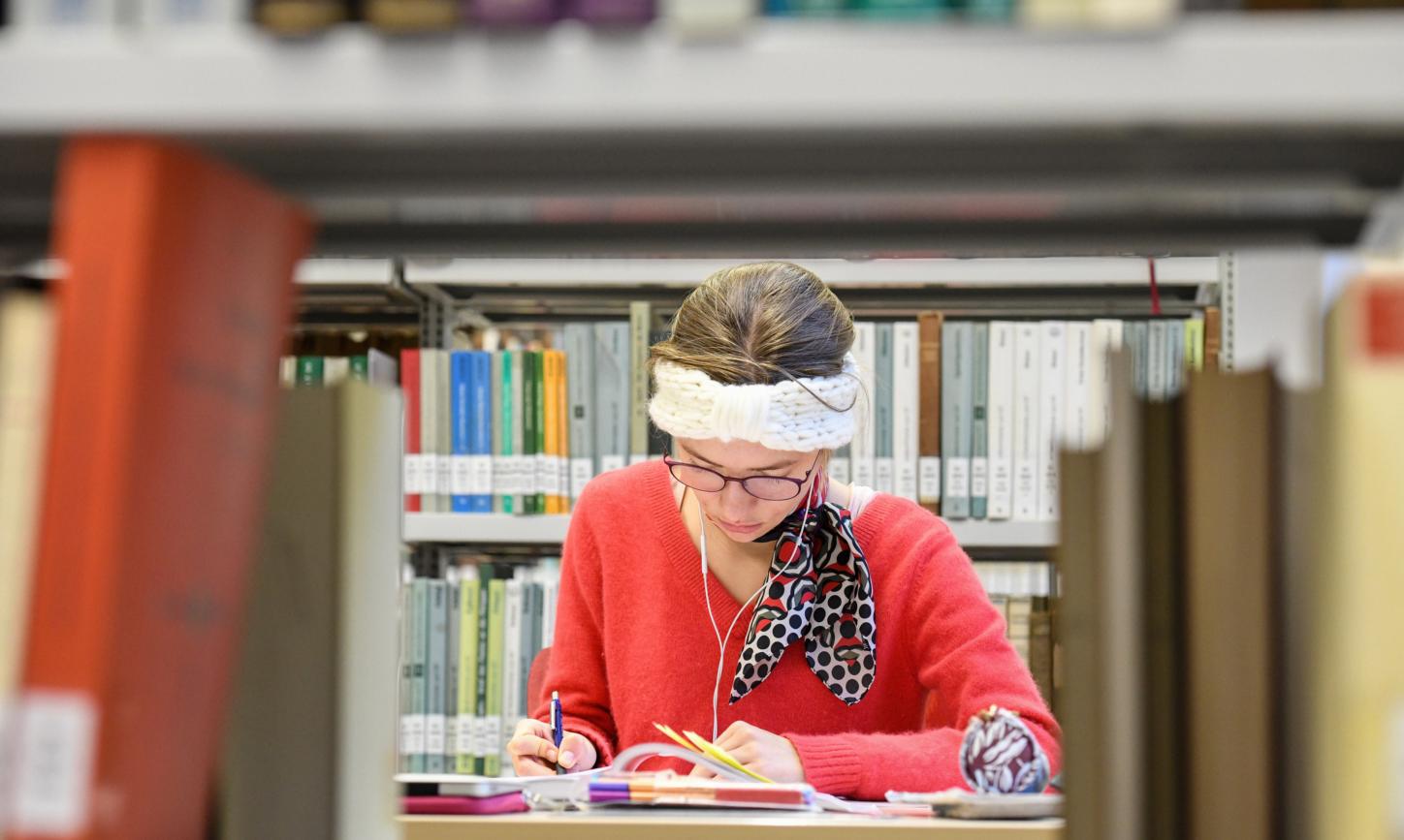 Eine Studentin sitzt in der Fachbibliothek für Evangelische und Katholische Theologie der Rheinischen Friedrich-Wilhelms-Universität Bonn.