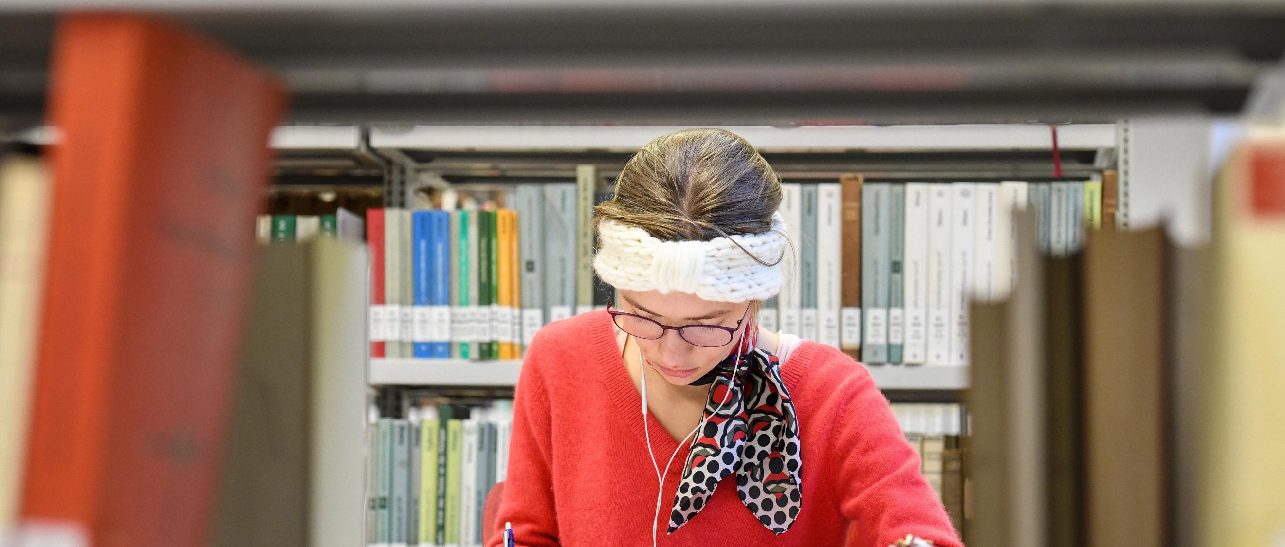 Eine Studentin sitzt in der Fachbibliothek für Evangelische und Katholische Theologie der Rheinischen Friedrich-Wilhelms-Universität Bonn.