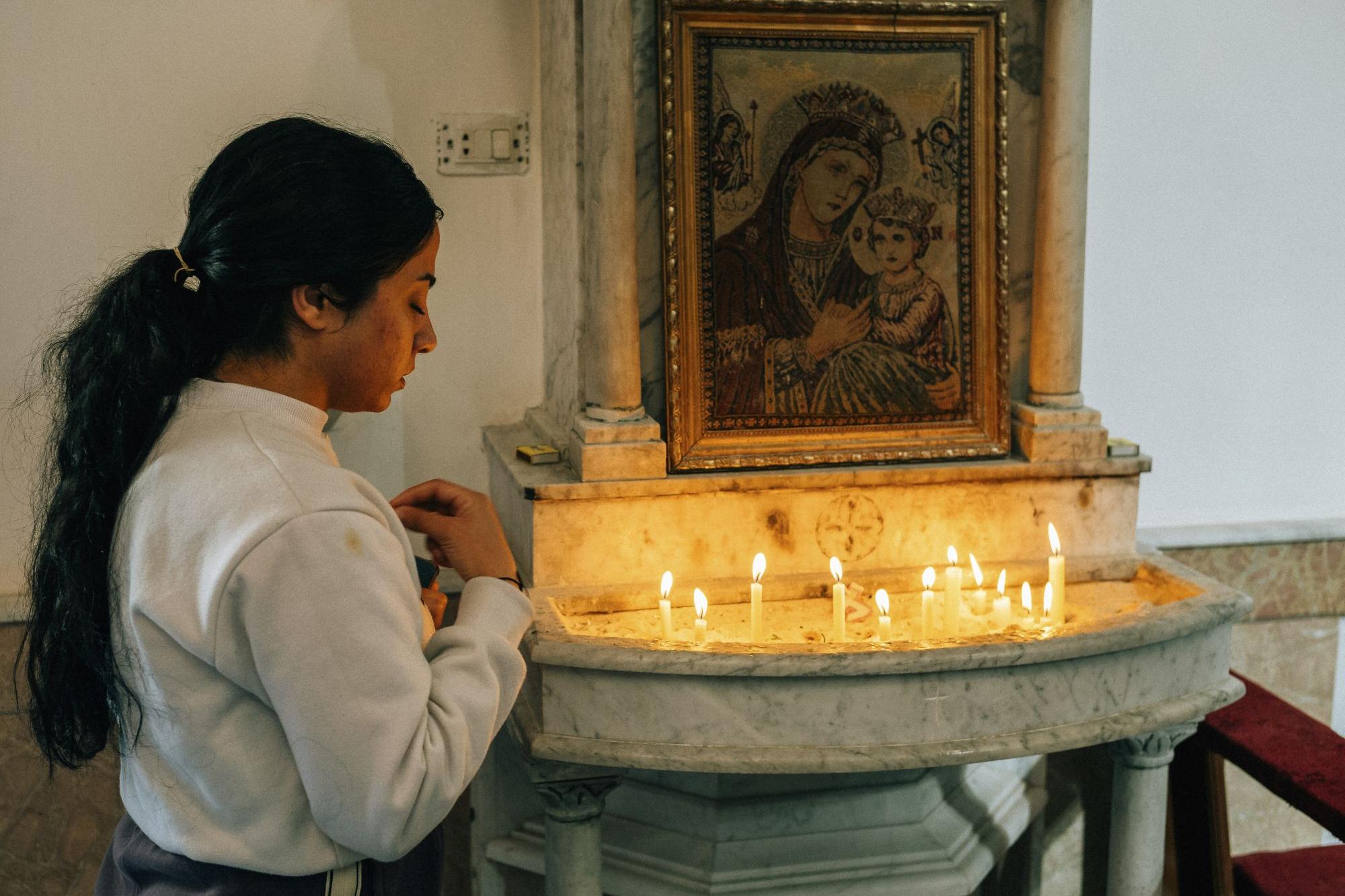 Ein Mädchen entzündet vor einer Ikone in der syrisch-katholischen Kathedrale  in Homs (Syrien) eine Kerze.