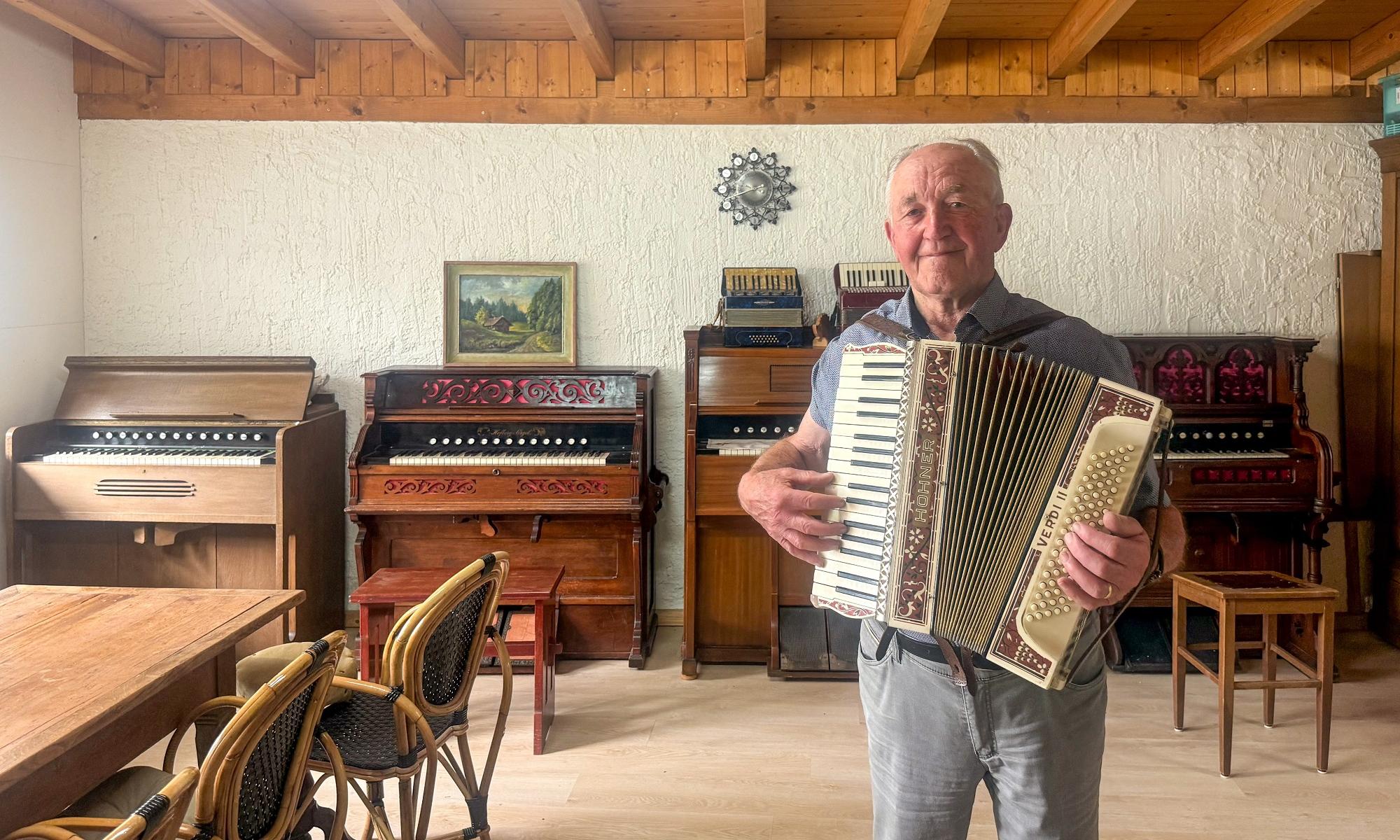 Ein Mann mit einem Harmonium steht vor verschiedenen alten Orgeln