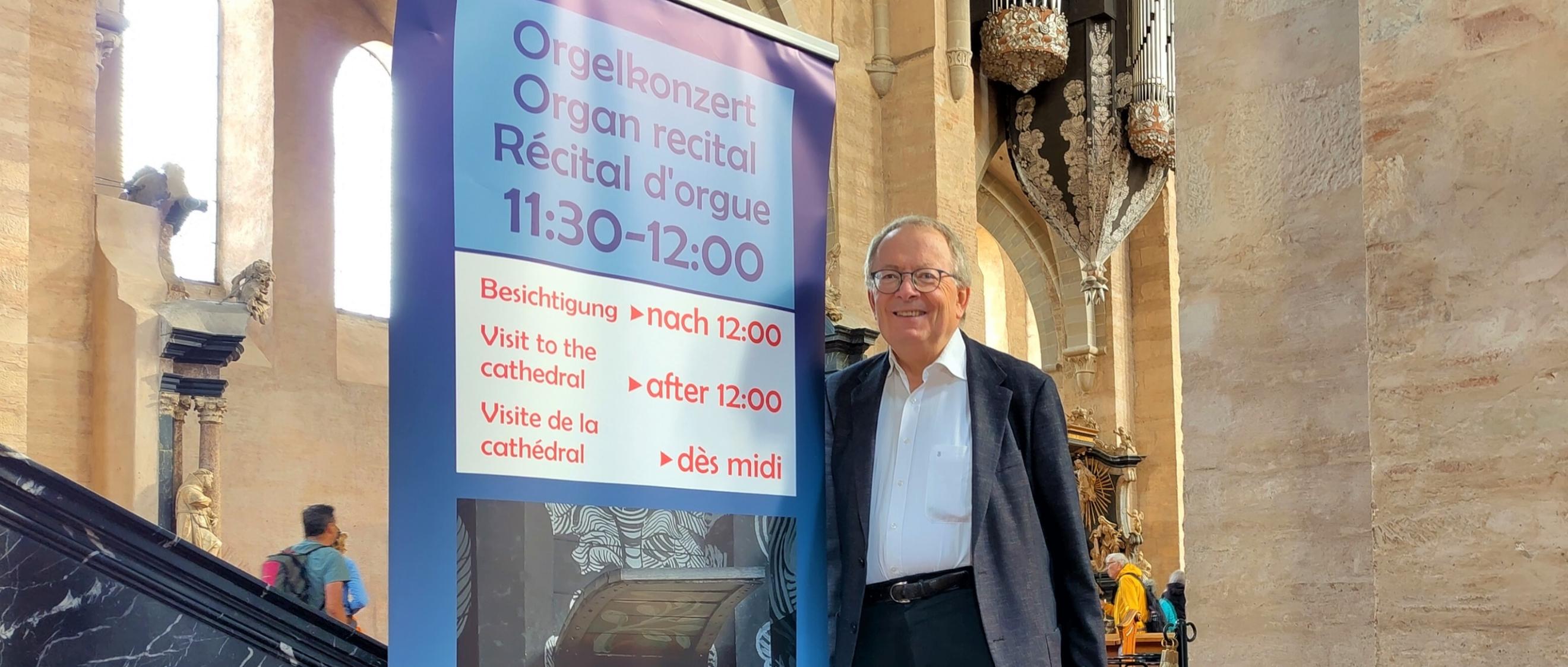 Ein Mann steht vor einem Plakat in einer Kirche