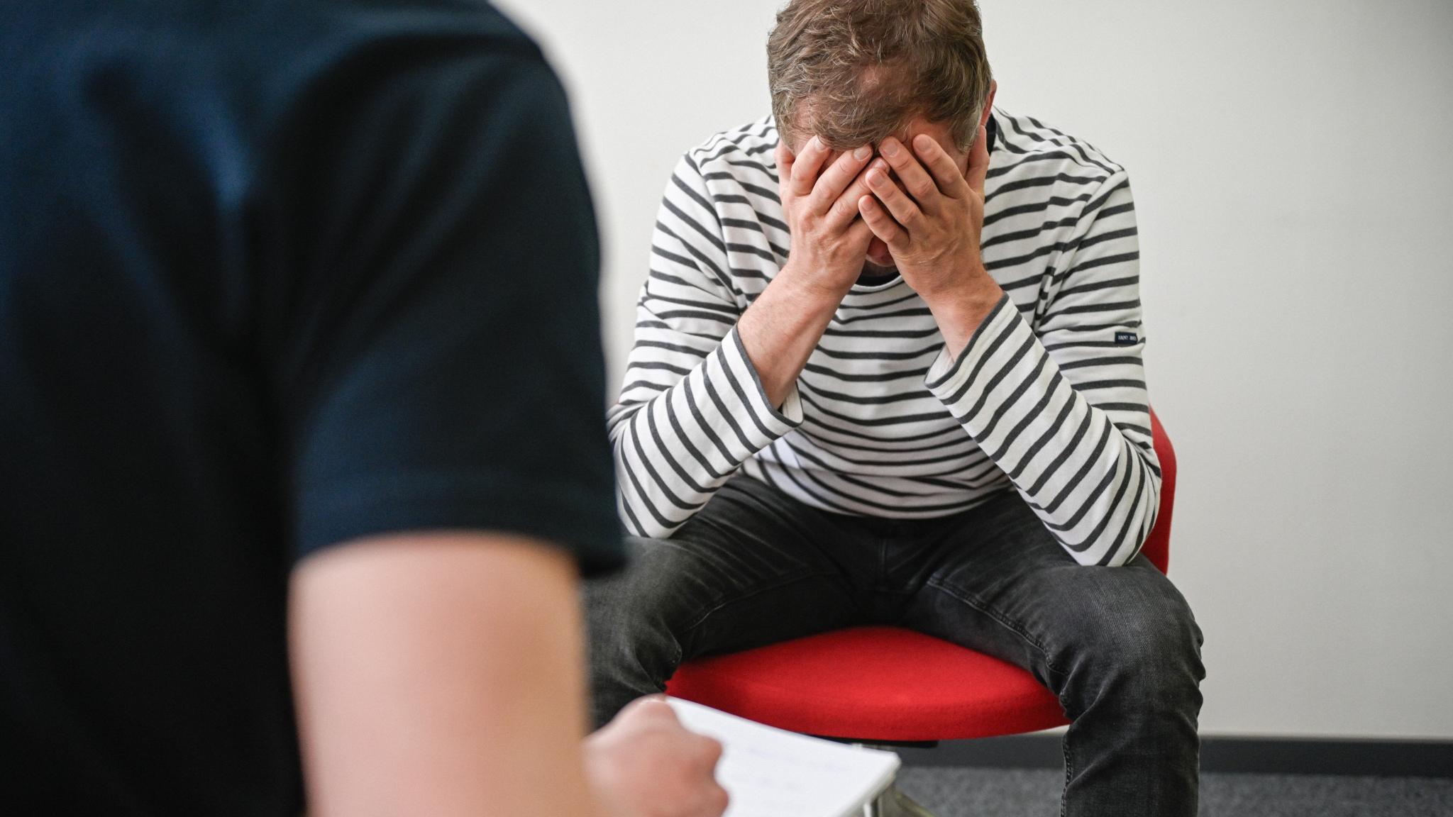 Mann, der sich den Kopf hält, im Gespräch mit Psychiater.