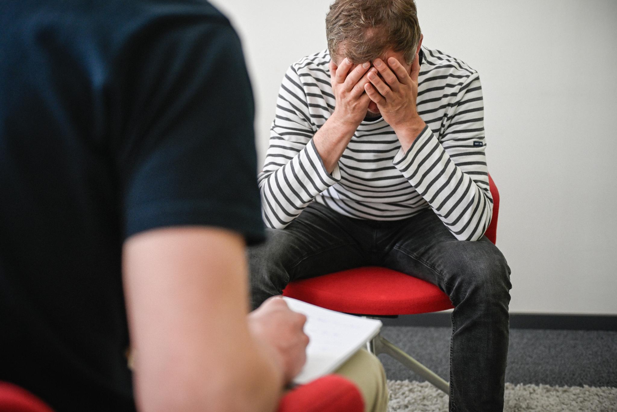 Mann, der sich den Kopf hält, im Gespräch mit Psychiater.