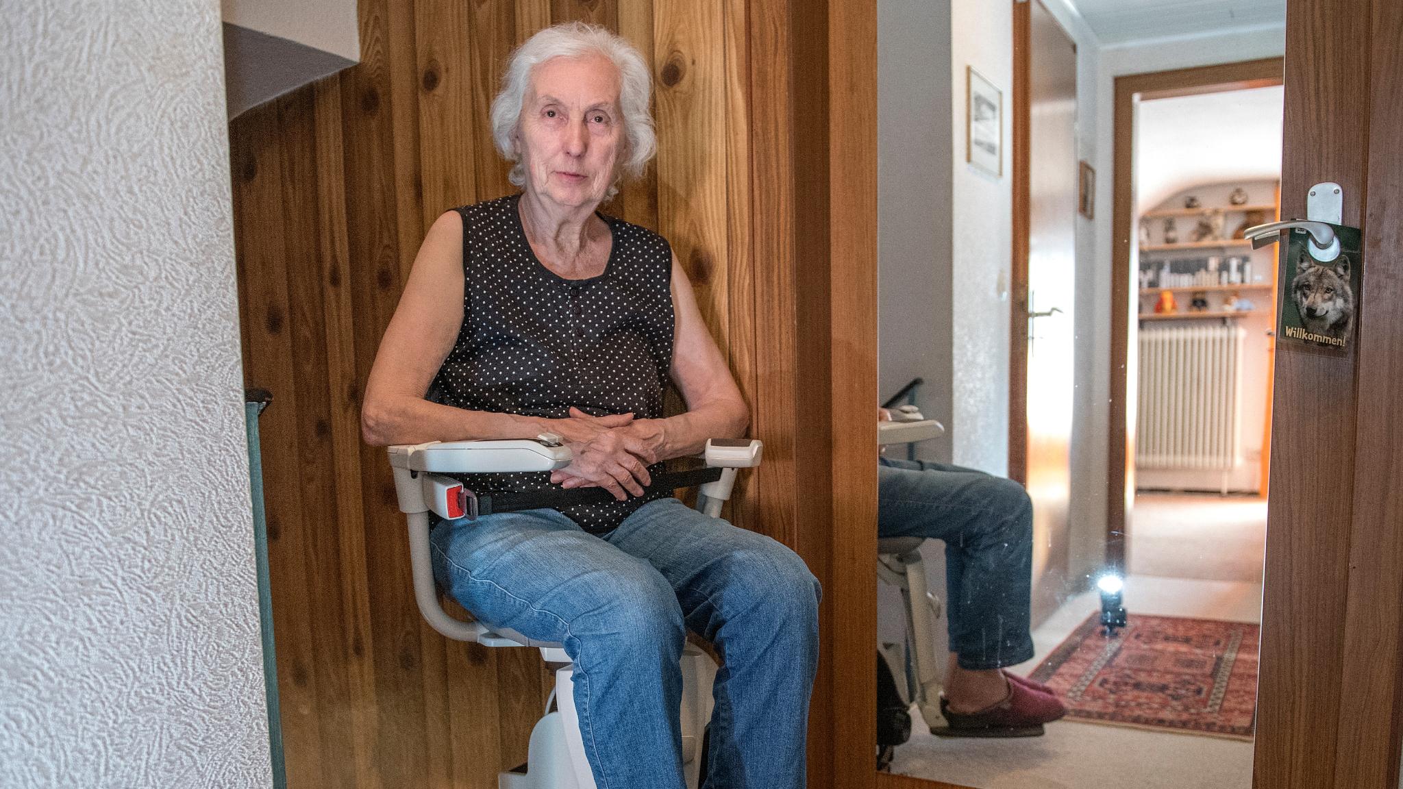 Eine Frau sitzt auf einem Treppenlifter.