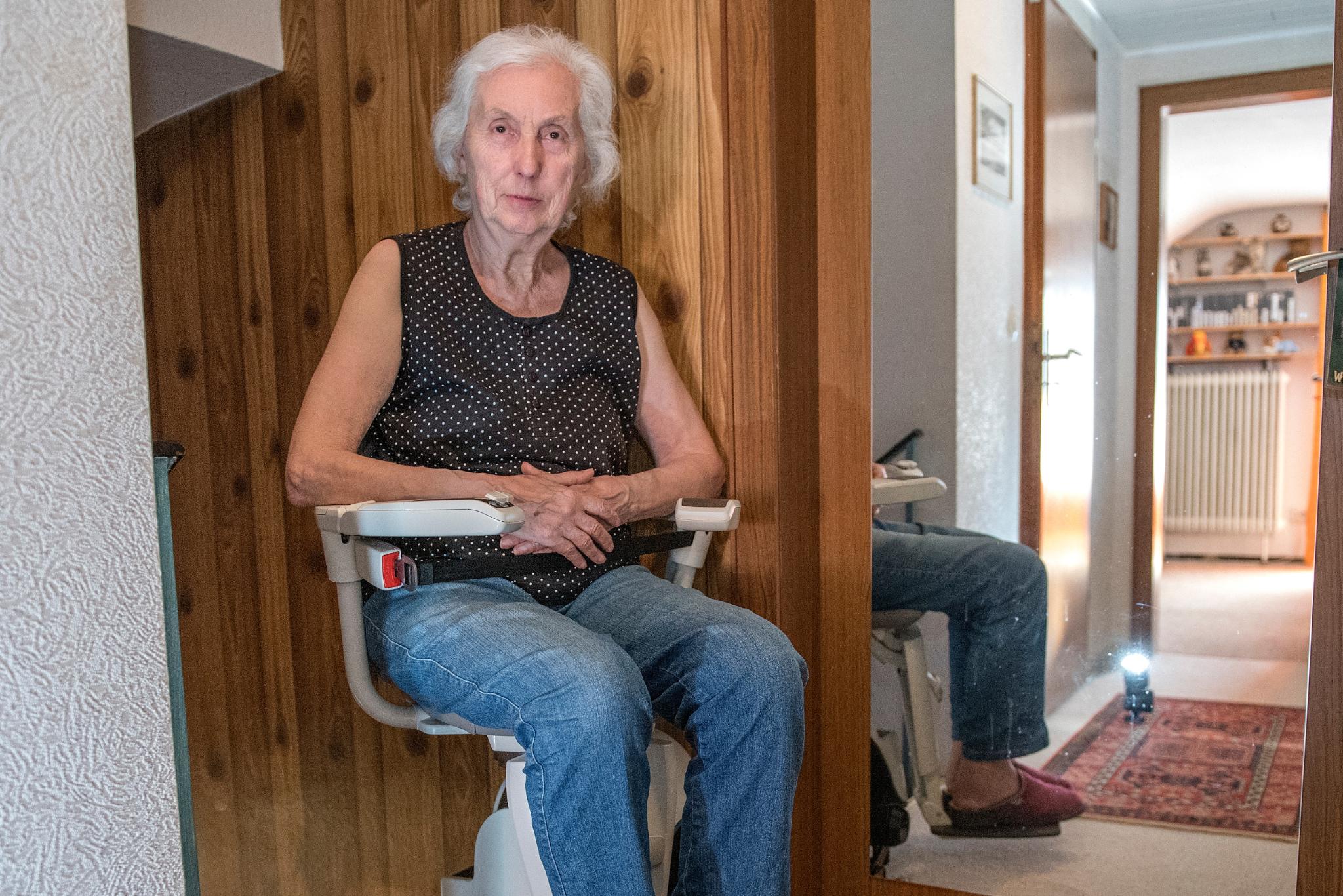 Eine Frau sitzt auf einem Treppenlifter.