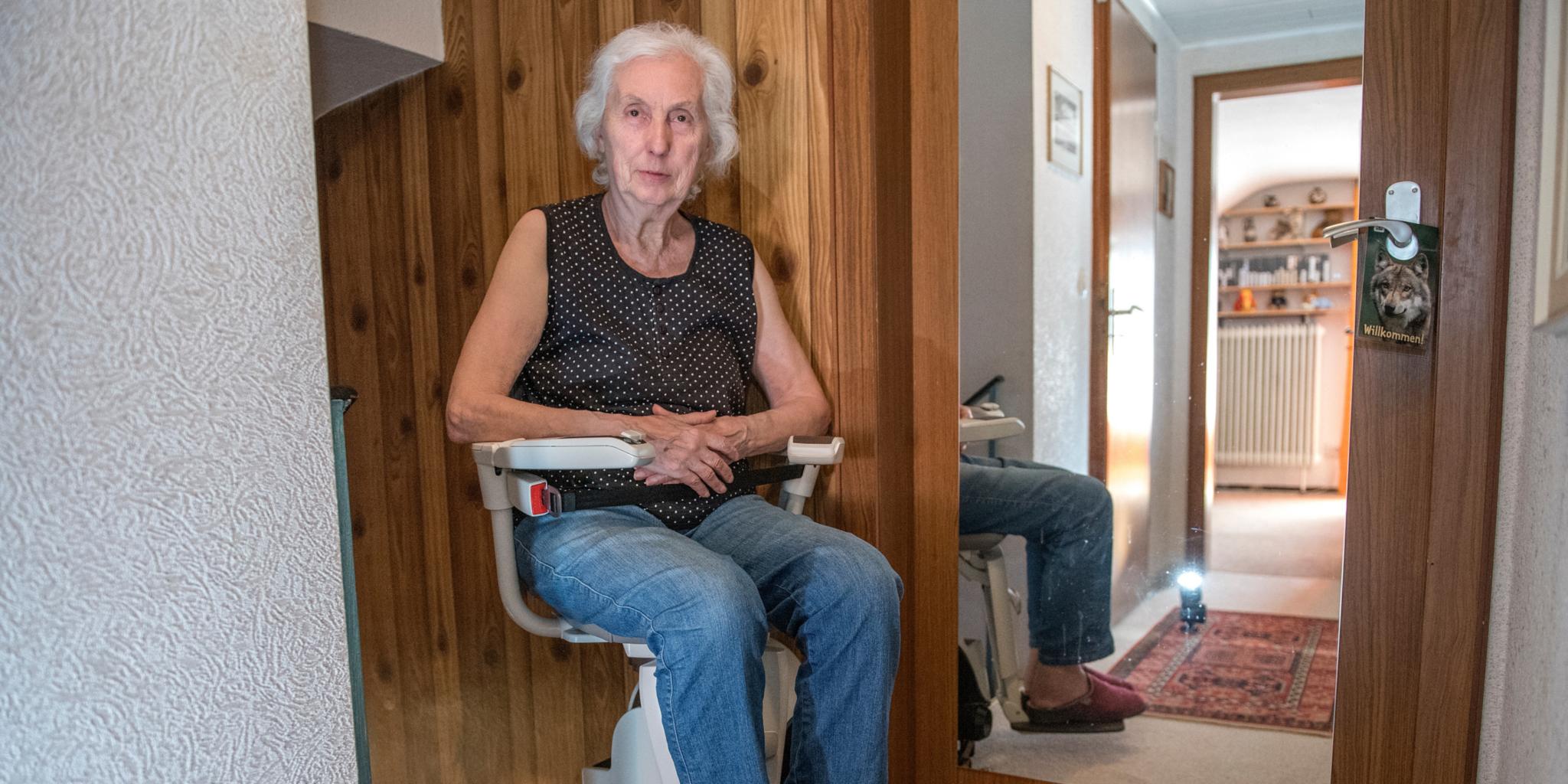 Eine Frau sitzt auf einem Treppenlifter. (c) imago images Eine Frau sitzt auf einem Treppenlifter.