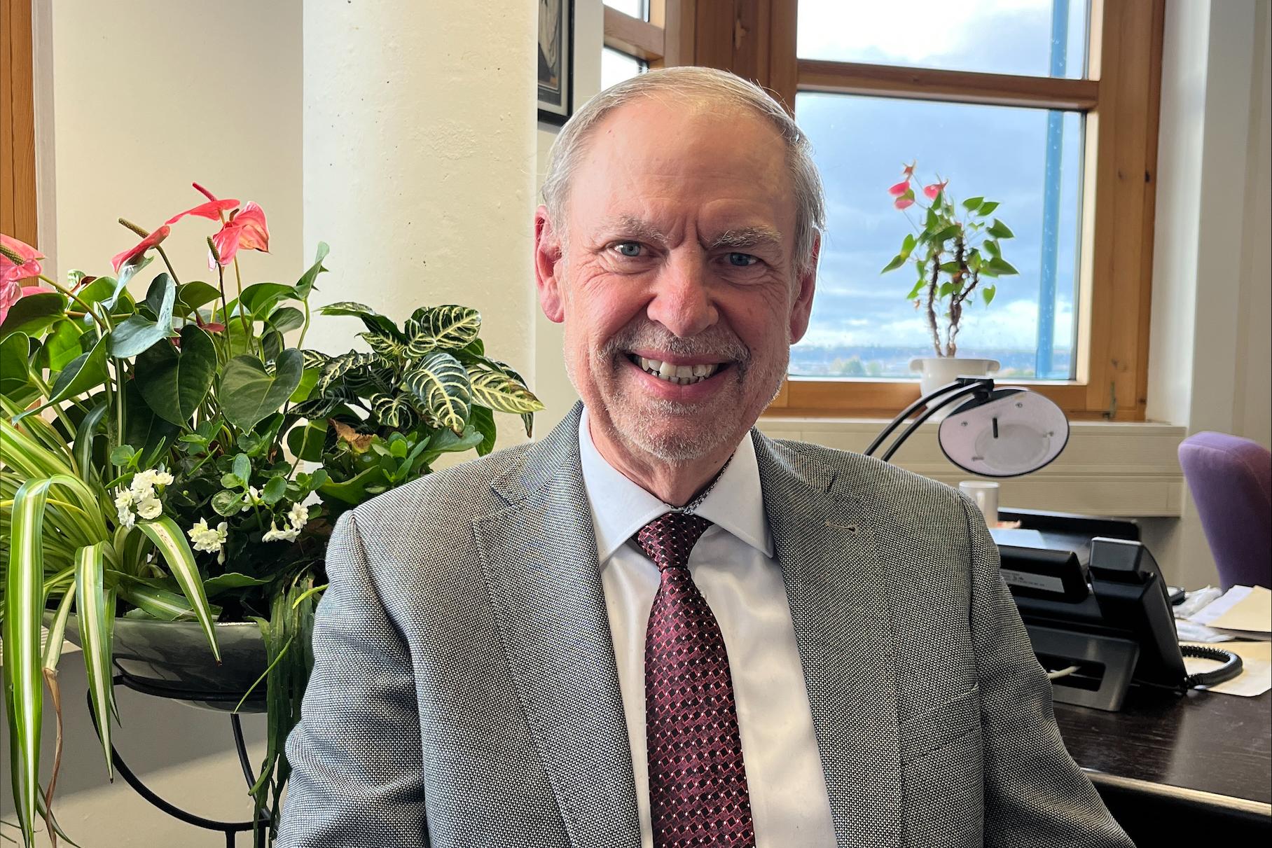 Ein Mann mit Krawatte blickt lächelnd in die Kamera