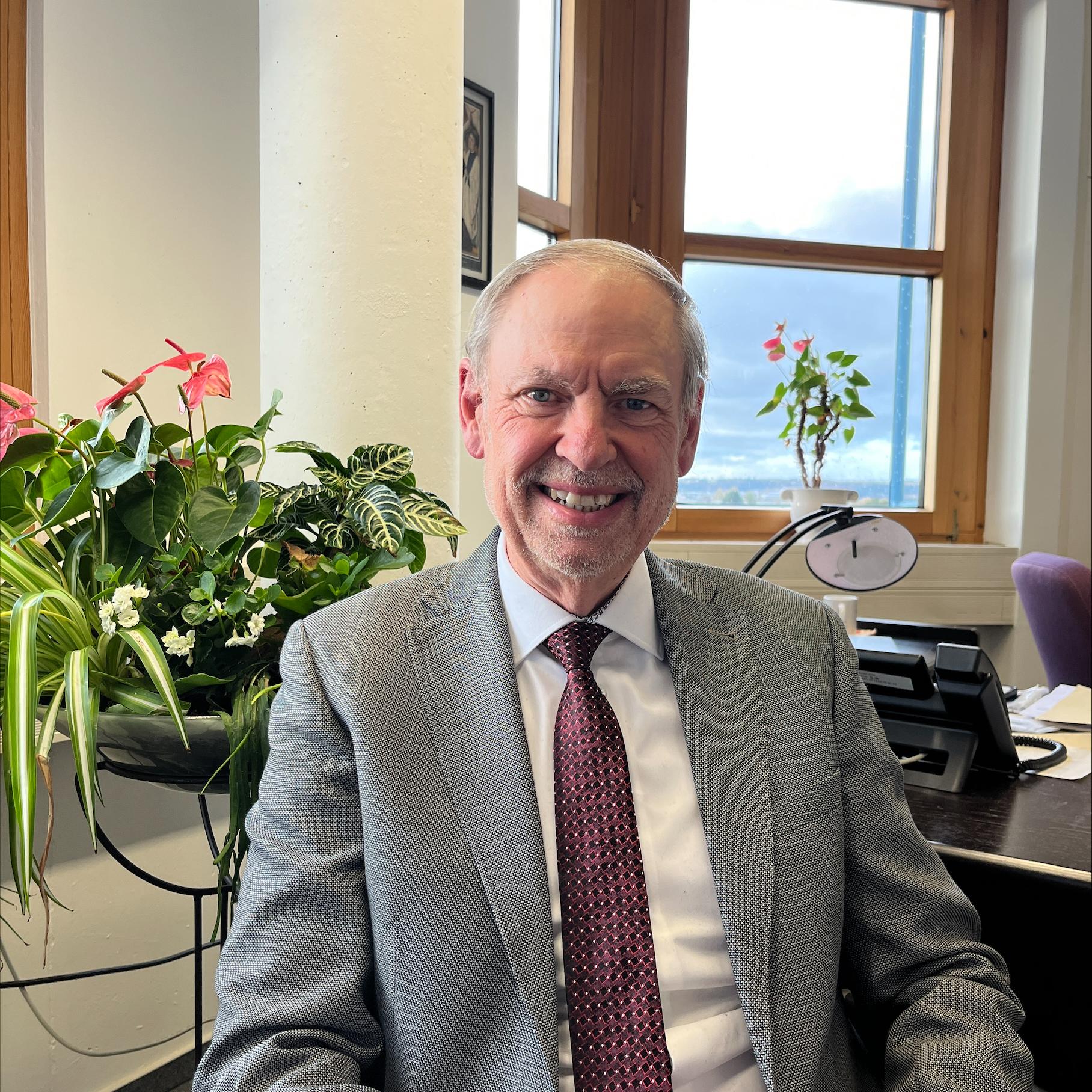 Ein Mann mit Krawatte blickt lächelnd in die Kamera