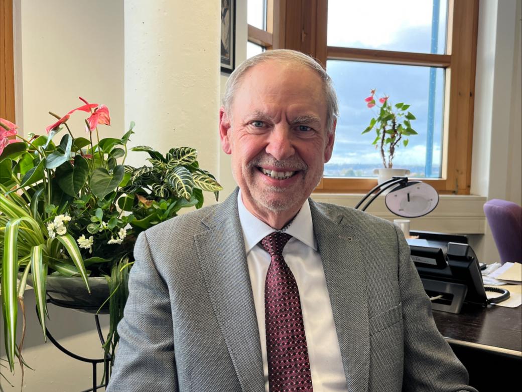 Ein Mann mit Krawatte blickt lächelnd in die Kamera