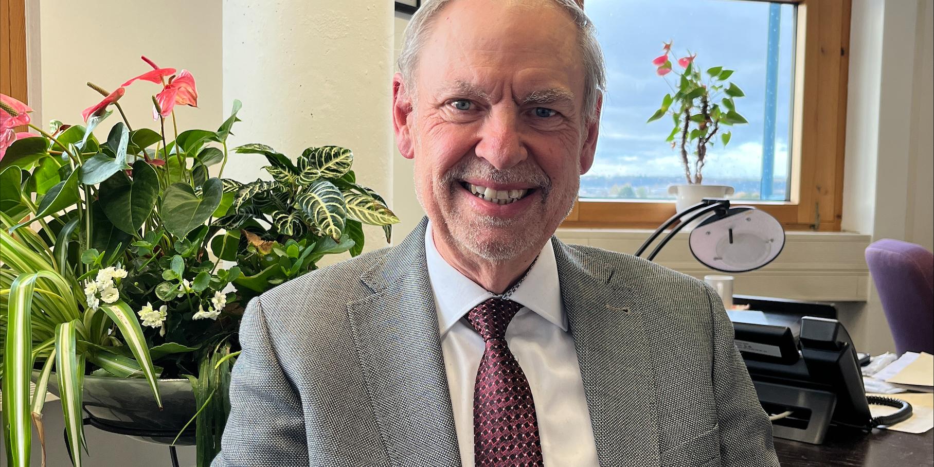 Ein Mann mit Krawatte blickt lächelnd in die Kamera