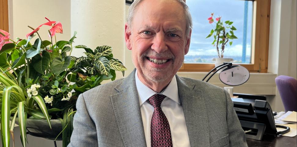 Ein Mann mit Krawatte blickt lächelnd in die Kamera