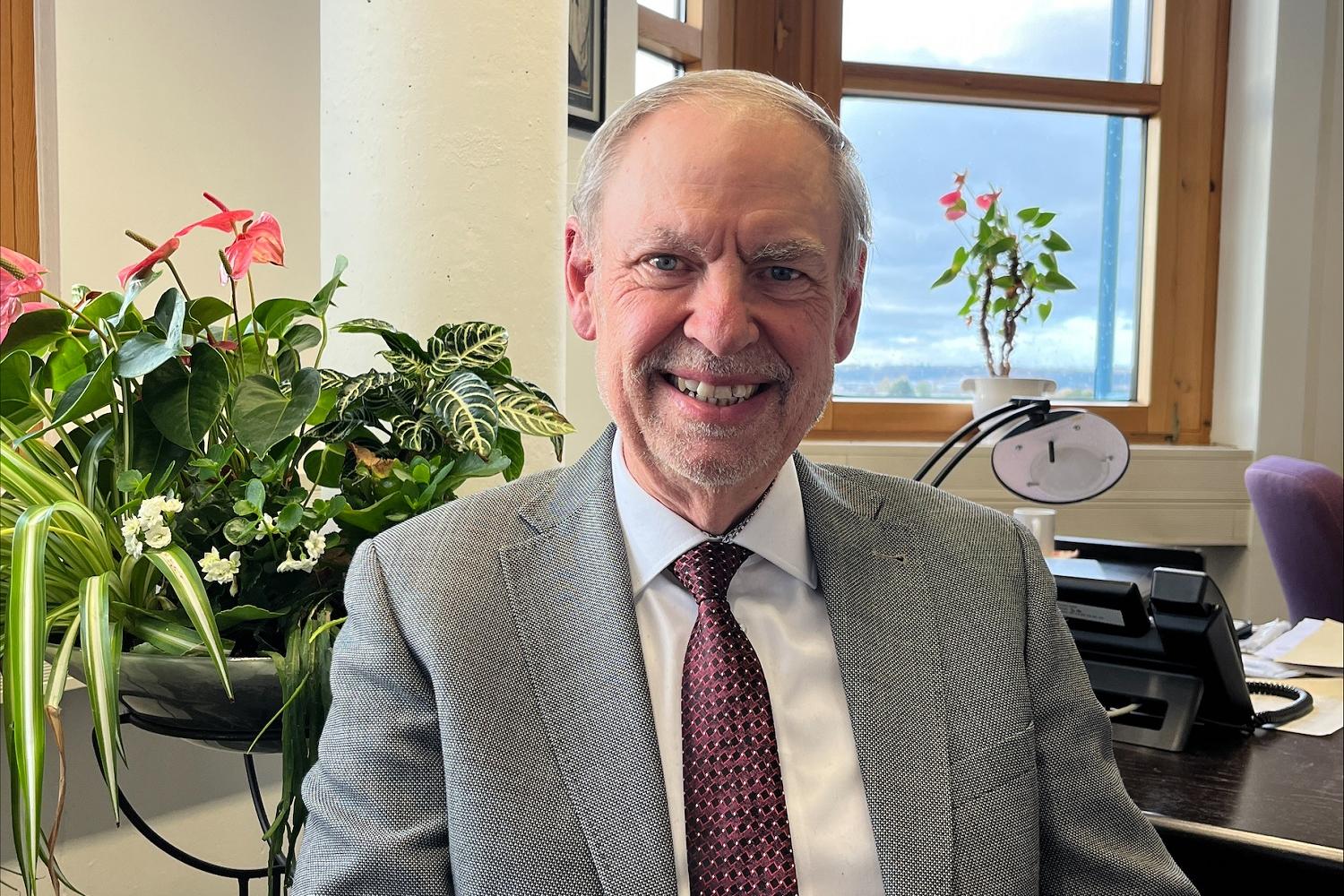 Ein Mann mit Krawatte blickt lächelnd in die Kamera