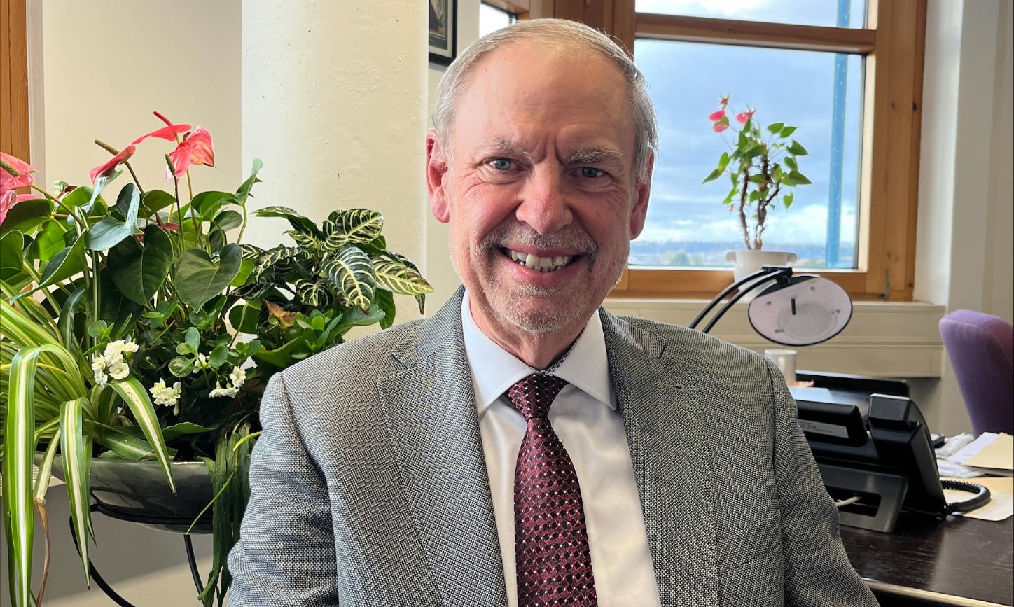 Ein Mann mit Krawatte blickt lächelnd in die Kamera