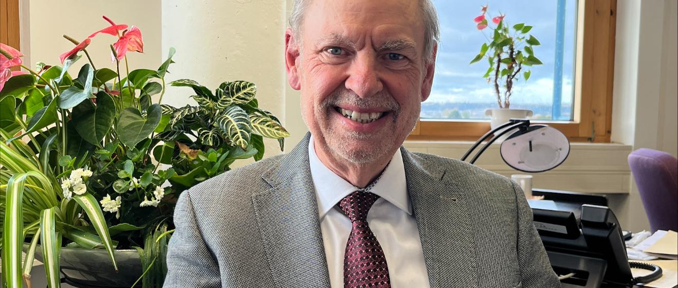 Ein Mann mit Krawatte blickt lächelnd in die Kamera