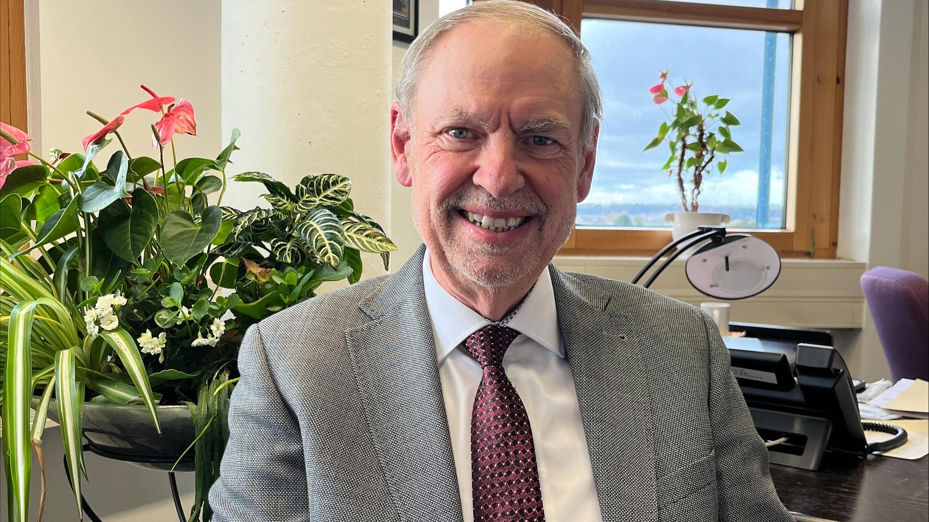 Ein Mann mit Krawatte blickt lächelnd in die Kamera