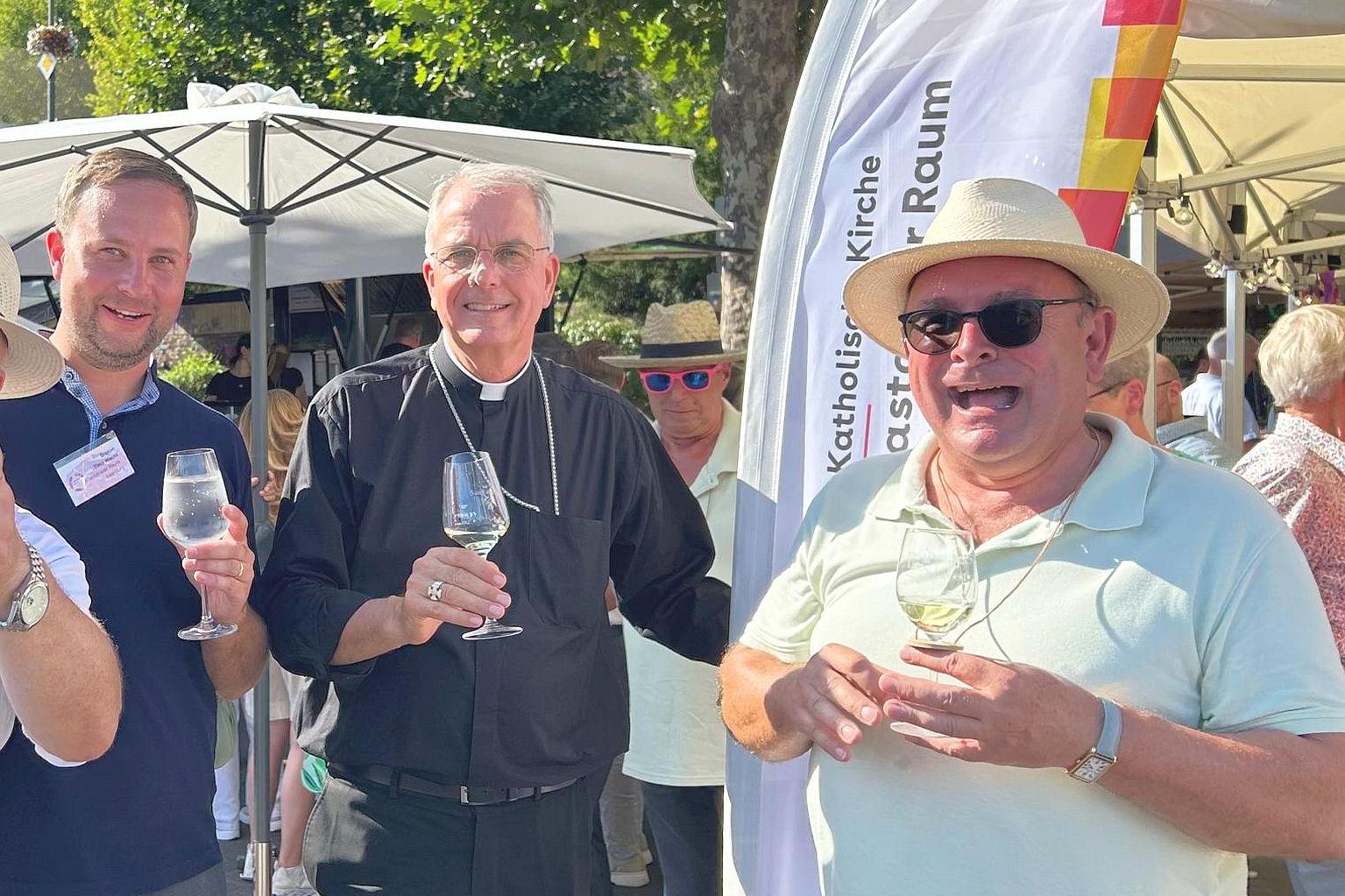 Drei Personen darunter  Weihbischof Jörg Michael Peters (Mitte) bei der Weinprobe.
