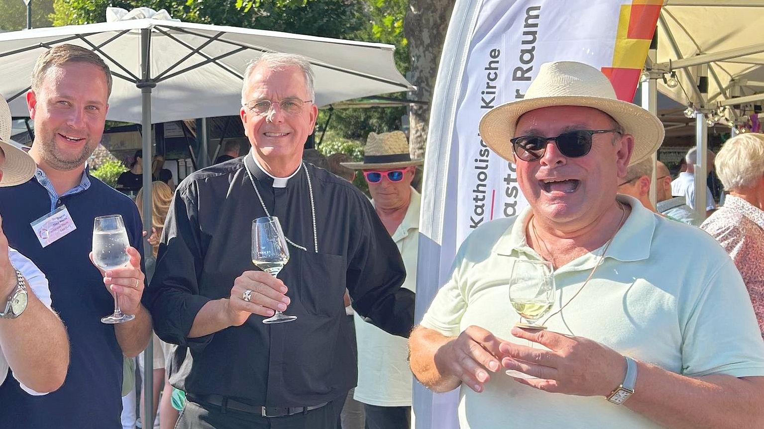 Drei Personen darunter  Weihbischof Jörg Michael Peters (Mitte) bei der Weinprobe.