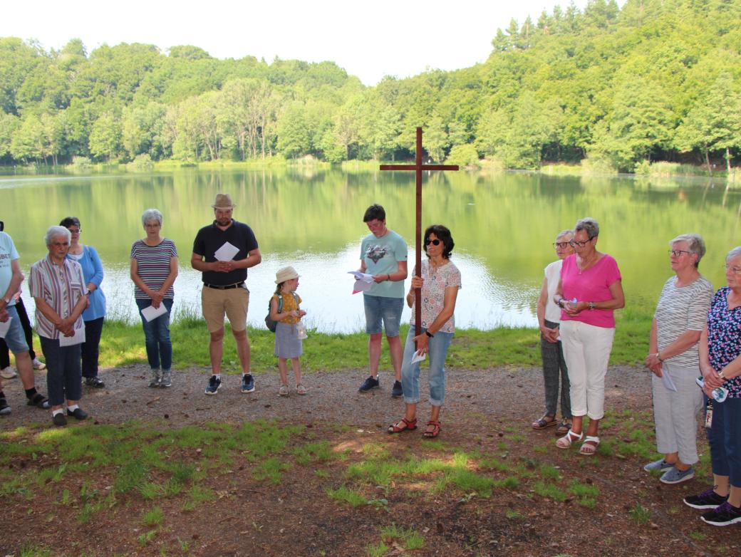 Menschen stehen mit einem Kreuz vor einem See