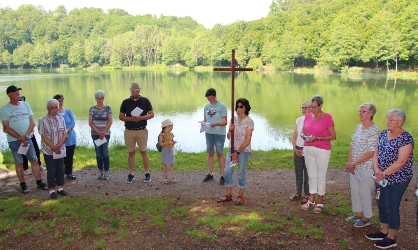 Menschen stehen mit einem Kreuz vor einem See