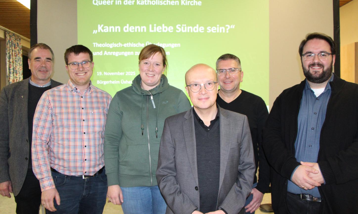 Sechs Personen stehen vor einer grünen Leinwand und lächeln in die Kamera