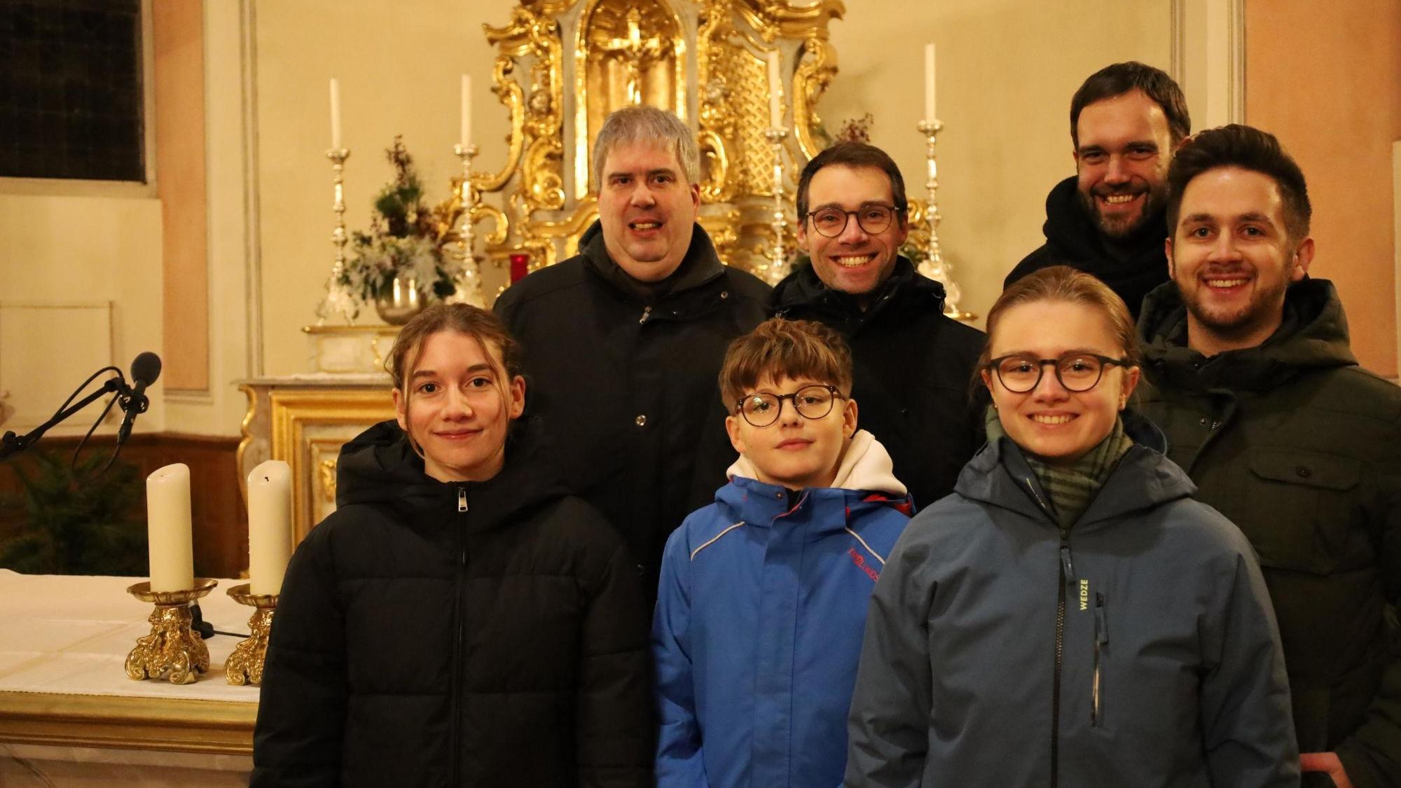 Eine Gruppe blickt in einer Kirche lächelnd in die Kamera