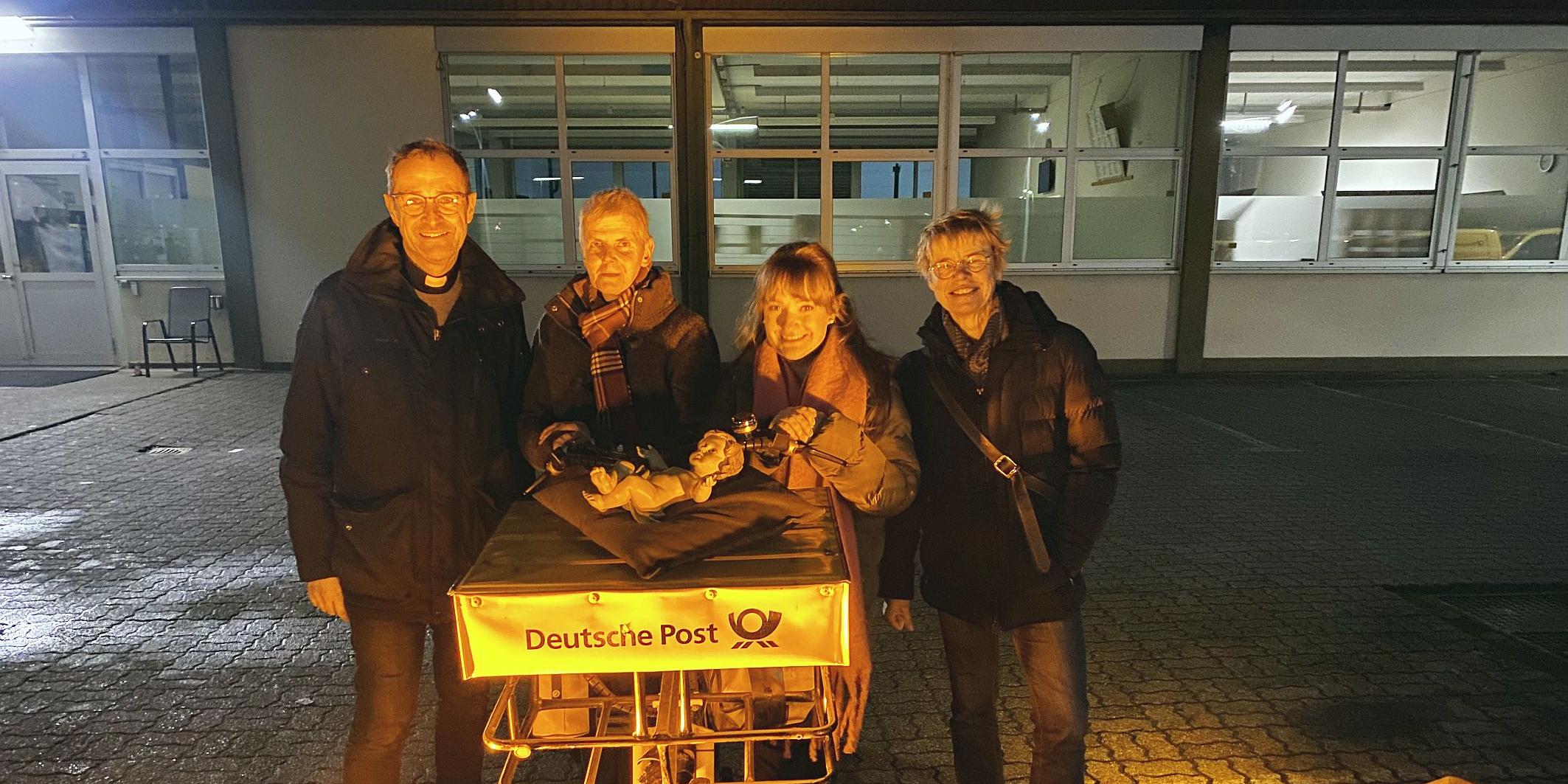 Pfarrer Jörg Meyrer, Ulrike Phiesel, Nadine Kreuser und Bärbel Knieps vom Vorbereitungsteam mit der Figur des Jesuskinds, das von einem Postboten per Fahrrad geliefert wurde. (c) Nadine Kreuser Pfarrer Jörg Meyrer, Ulrike Phiesel, Nadine Kreuser und Bärbel Knieps vom Vorbereitungsteam mit der Figur des Jesuskinds, das von einem Postboten per Fahrrad geliefert wurde.