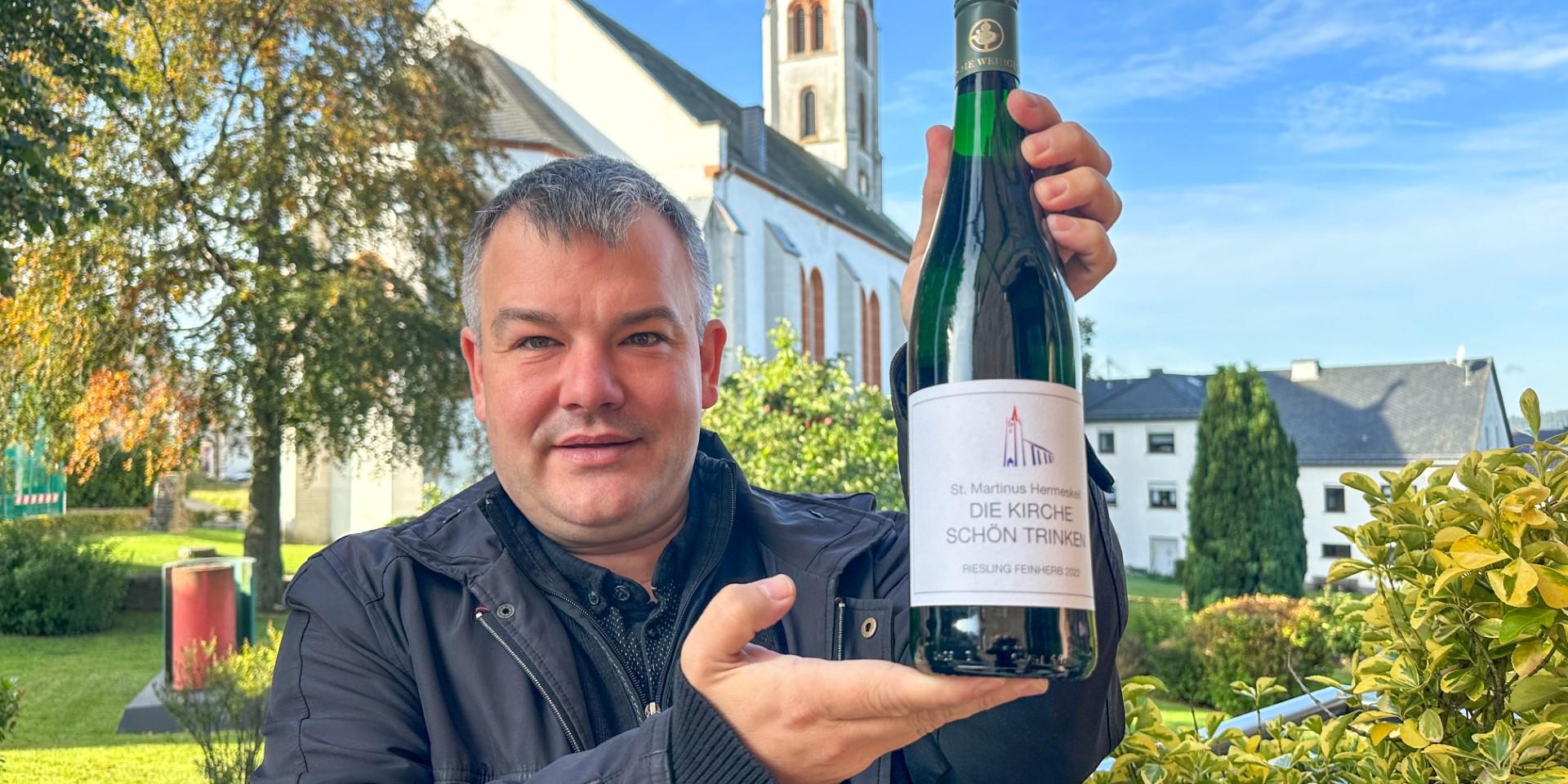 Dechant Christian Heinz präsentiert vor der St. Martinus-Kirche eine der 5000 Flaschen des Charity-Weins. (c) Rolf Lorig Dechant Christian Heinz präsentiert vor der St. Martinus-Kirche eine der 5000 Flaschen des Charity-Weins.